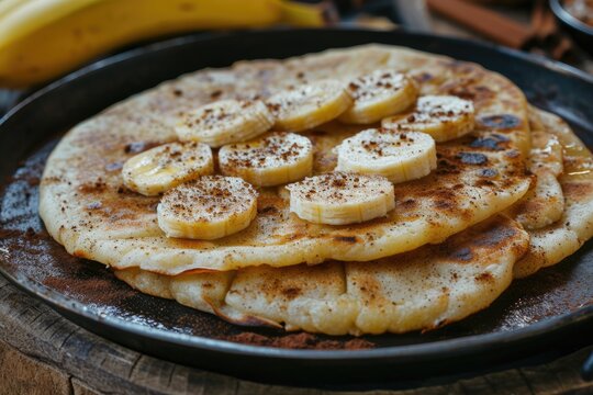 Selective focus on cassava based flatbread casabe bammy beiju bob biju topped with banana and cinnamon on a pan Copy space available