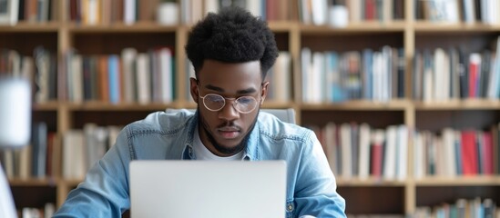 A young male student is gaining knowledge remotely through online learning using his laptop.