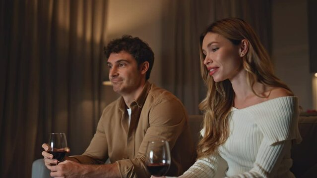 Couple spending first date in cozy evening apartment holding wineglasses closeup