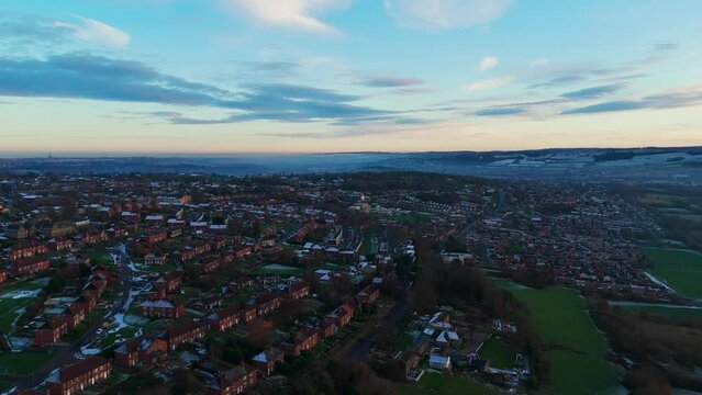 Red brick terraced houses in the UK. Bathed in winter sunlight on a cold mist winters day in January, Sunset aerial footage of an urban industrial town in Yorkshire England