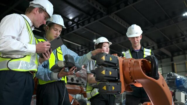Group of engineers and technicians working together in a robotic arm factory. Inspecting robot arm before delivering to customers