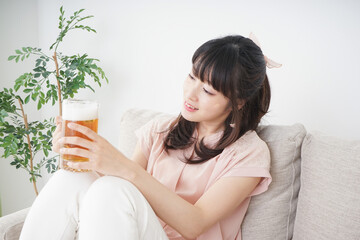 Obraz na płótnie Canvas 自宅でビールを飲む若い女性