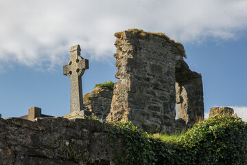 Celtic cross and ruins at Donegal Abbey against blue sky, Donegal, Ireland 