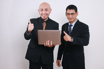 Two Asian businessmen using laptop and giving thumbs up 