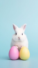 Obraz premium A cute white rabbit sitting with pastel pink and yellow Easter eggs on a light blue background.
