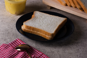Slices of Toast Loaf White Bread (Shokupan or Roti Tawar) for Breakfast on a Black plate, Served with margarine and jam.