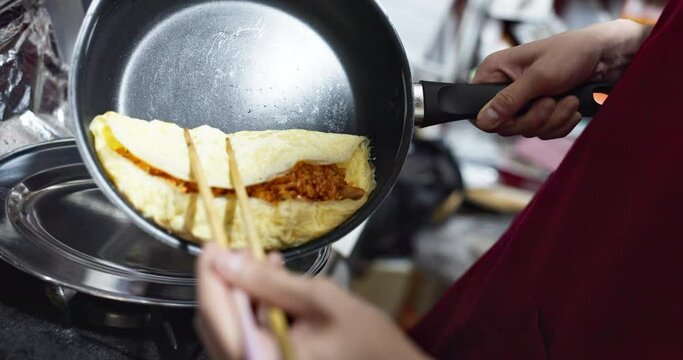 Hands, food or omurice in kitchen with chef for Japanese lunch, dinner or healthy meal for nutrition. Person, omelette and preparation or cooking with chopsticks in restaurant, cafe or small business