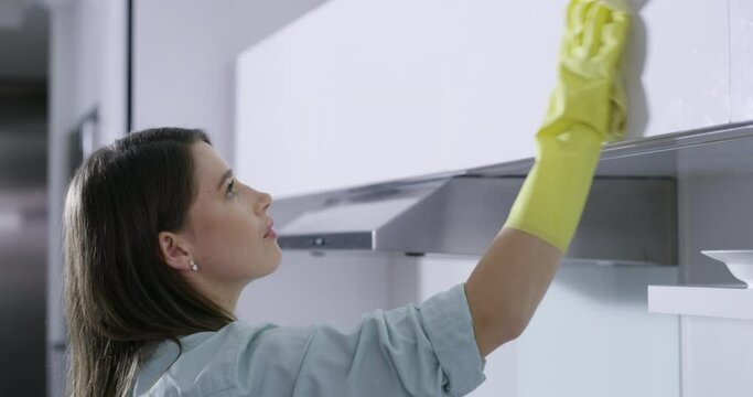 Woman, furniture or cleaner in kitchen for cleaning, housekeeping or germ or bacteria removal. Maid, female person or housekeeper wiping wooden surface or cupboards for healthy hygiene at home
