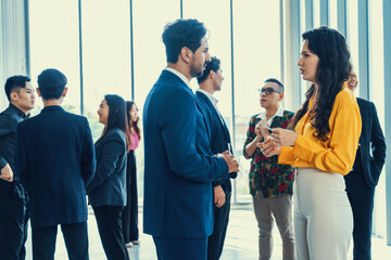 Businessman discussing with female leader about financial project intentionally while standing rounded with business people exchanging financial experience. Side view. Office hallway. Intellectual. - obrazy, fototapety, plakaty