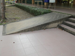 Disabled ramp or incline concrete installed at the public park beside the stair. Standard construction for handicap and old aged people in Asia. 