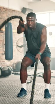 Black man, fitness and battle rope at gym for workout, strength or muscle endurance on floor. Serious African male person, bodybuilder or athlete in sweat, exercise or intense power at health club