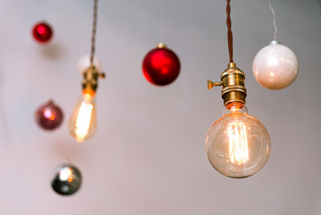 Edison Bulbs and Christmas Baubles Hanging Decor. Warmly lit Edison bulbs hang alongside festive...