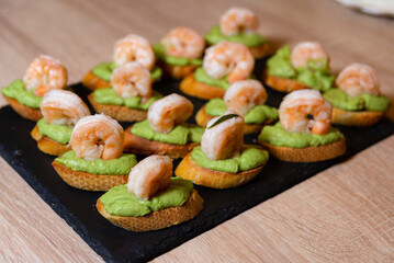 Shrimp and Avocado Crostini on Black Slate. Shrimp and avocado crostini appetizers arranged on a black slate board, perfect for an elegant party or gathering.