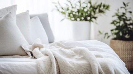Crisp white bedding in a bright bedroom with decorative pillows and a green plant in the background.