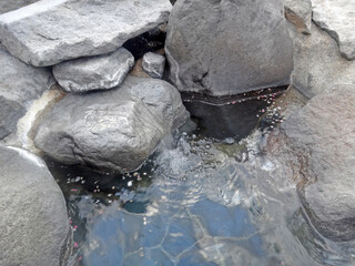 Traditional japanese onsen outdoor bath tub, water flowing from hot spring stone fountain