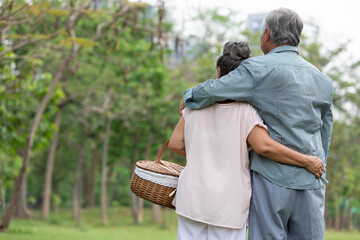 back senior couple looking forward to something in the park