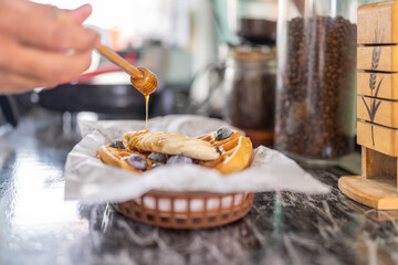 Cook adding honey to the top of a waffle