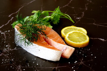 Salmon fillet with lemon, parsley and dill against black background