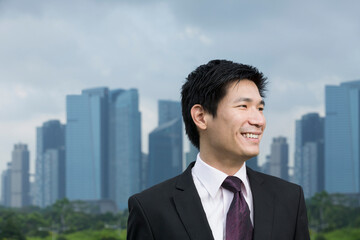 Happy asian business man in front of city.