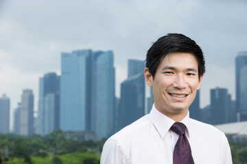 Happy asian business man in front of city.