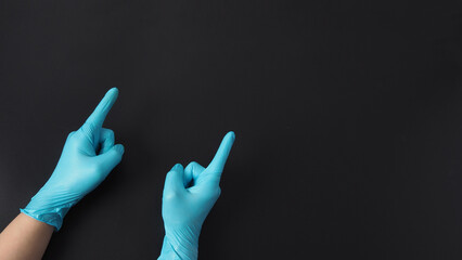 Two hand is wear blue doctor gloves and point the finger on black background.