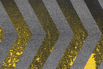Chevrons jaunes sur asphalte, peinture dégradée sur route