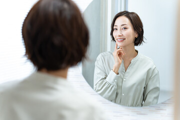 鏡を見て肌を触る日本人女性