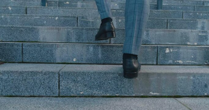 Businessman in strict suit climbs steps to business center. Ambitious businessman decisively goes to important meeting regarding profitable deal. Businessman confidently moving towards intended goal.