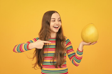 Funny teenage girl hold citrus fruit pummelo or pomelo, big green grapefruit isolated on yellow...
