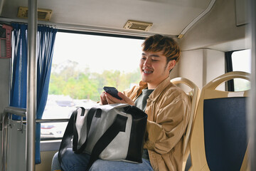 Happy young man tourist using a smartphone in public transportation. People and transportation concept