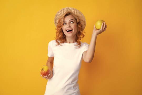 Portrait of a smiling happy girl with apple isolated over yellow background.