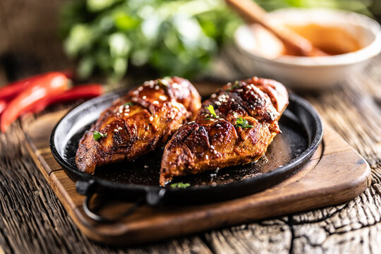 Marinated grilled chicken breast in BBQ sauce and served on a cast iron pan - Close up
