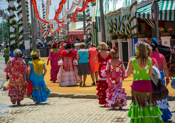 a crowd of women in flamenco dresses through the narrow streets of the Feria of Seville