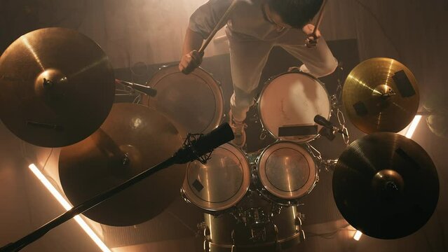 Top view rock musician drummer plays drums in a dark studio in smoke. Music band having rehearsal. Music or song recording