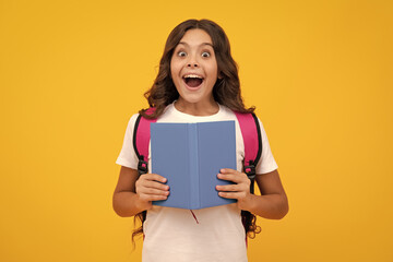 Schoolchild, teenage student girl with school bag backpack hold book on yellow isolated studio...