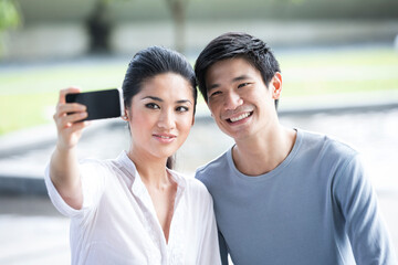 Asian couple using tablet to take a selfie.
