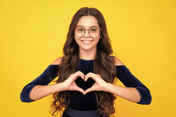 Child hands making sign heart by fingers. Cheerful lovely romantic teen girl hold red heart symbol...