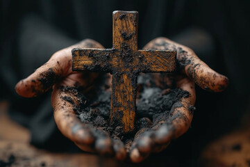 Dirty male hands holding a wooden cross on a black background - obrazy, fototapety, plakaty
