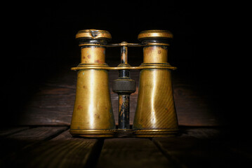 Retro binoculars on the old wooden desk table background front view close up. Travel background.