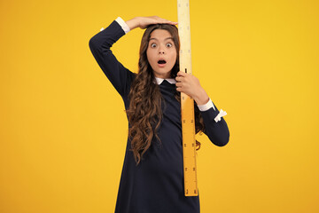 Back to school. Teenager school girl on yellow background. School supplies. Surprised emotions of...