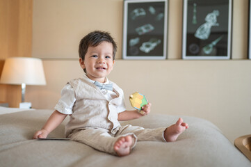 Fototapeta premium Baby boy's sitting on a bed wearing a suit