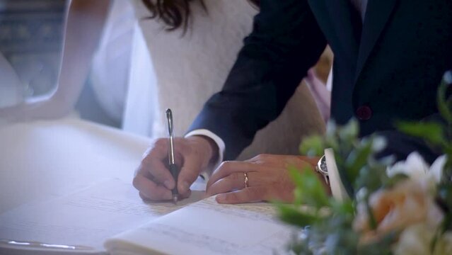 A newly wed groom signing their marriage license, officially legalizing their union.
