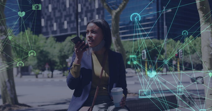 Image of networks of connections with icons over woman using smartphone wearing face mask