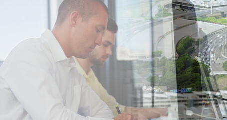 Image of diverse business people in office over cityscape