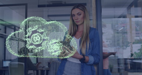 Image of data processing with cloud and cogs over caucasian businesswoman in office
