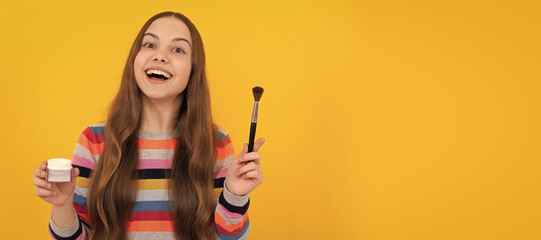 Happy kid apply cosmetics with foundation brush yellow background, makeup. Cosmetics for teenager child, poster design. Beauty kids makeup, banner with copy space.