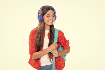 Back to school. Schoolgirl student in headphones with school bag backpack on isolated studio background. School and education concept. Portrait of happy smiling teenage child girl.