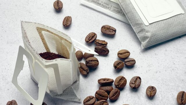 Drip coffee paper bags with coffee beans on a grey concrete background