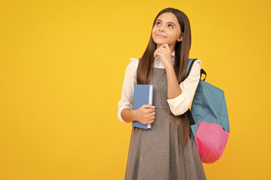Schoolgirl, teenage student girl hold book on yellow isolated studio background. School and education concept. Back to school. Thinking teenager girl, thoughtful emotion.