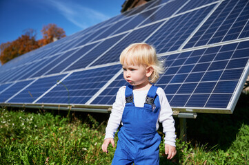 Little cute boy wondering how does solar panel work. Adorable blond kid in blue work overalls on...